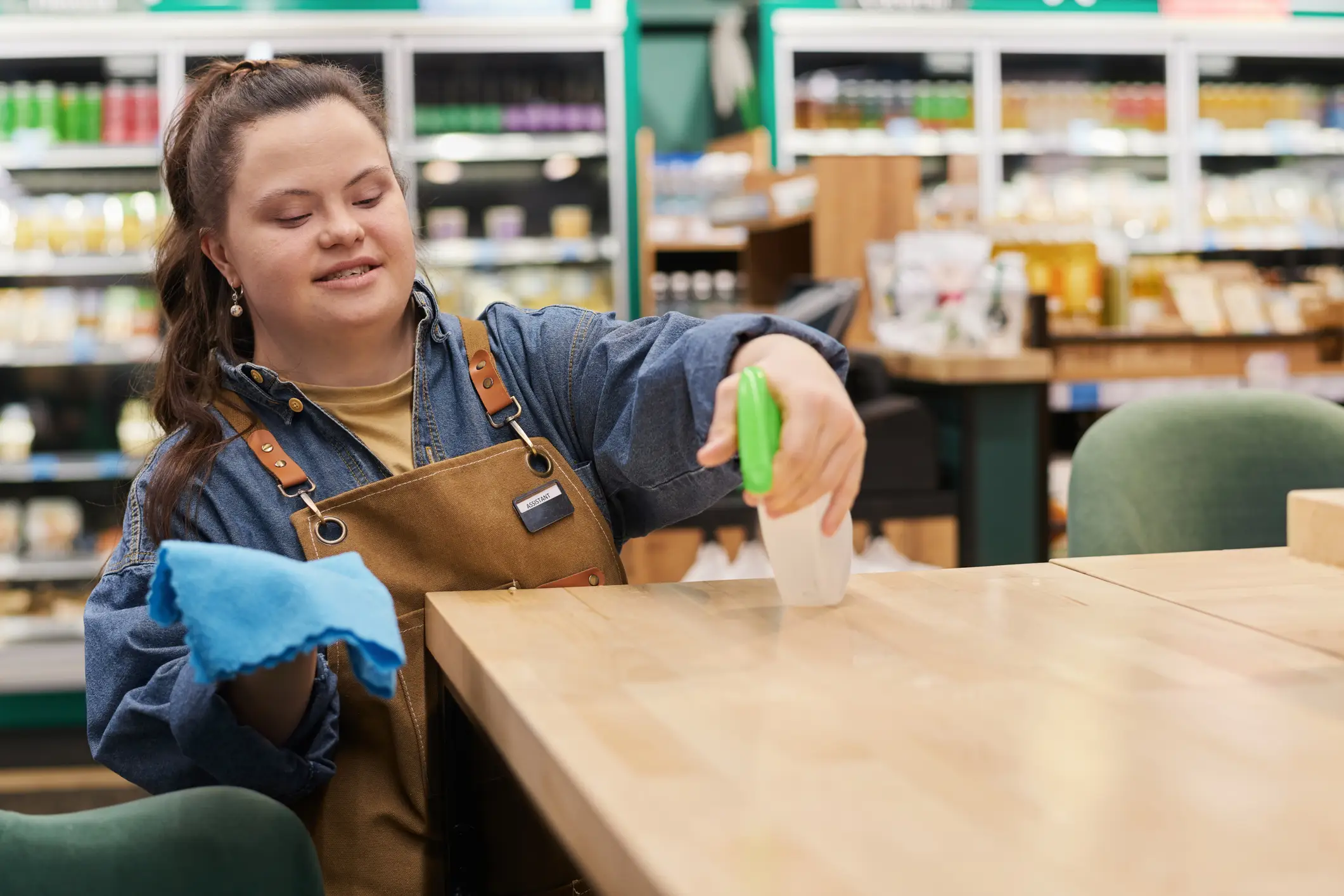 A woman in an apron is cleaning the table.